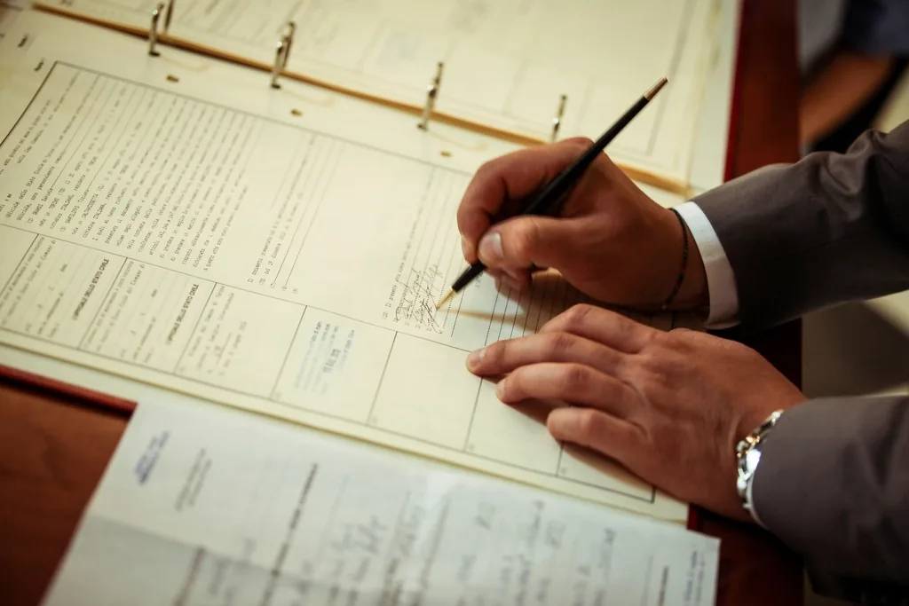 Hands signing a formal contract document with a fountain pen